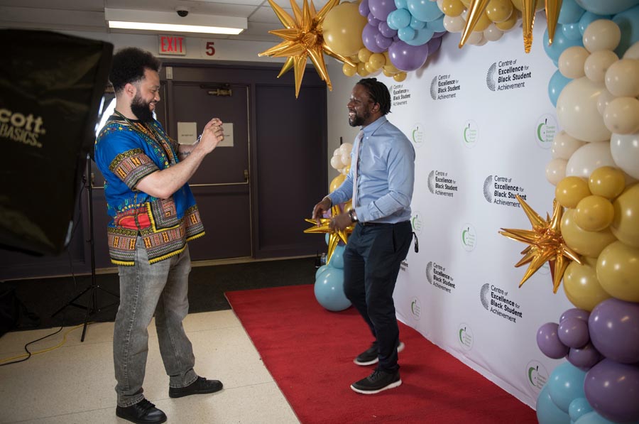 Decorative photo backdrop with balloons. A man takes the photo of another. Open Gallery